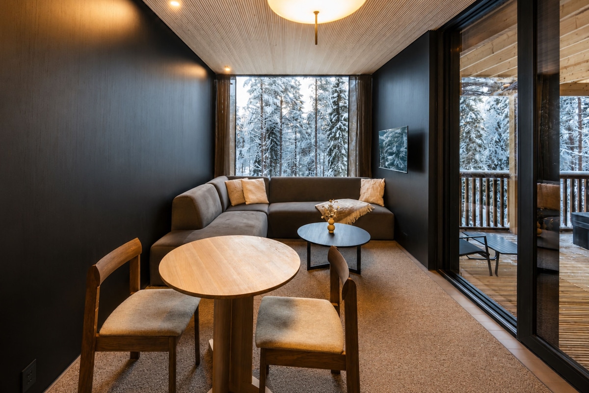 Un interior moderno con un sofá modular, una mesa redonda de madera y sillas.