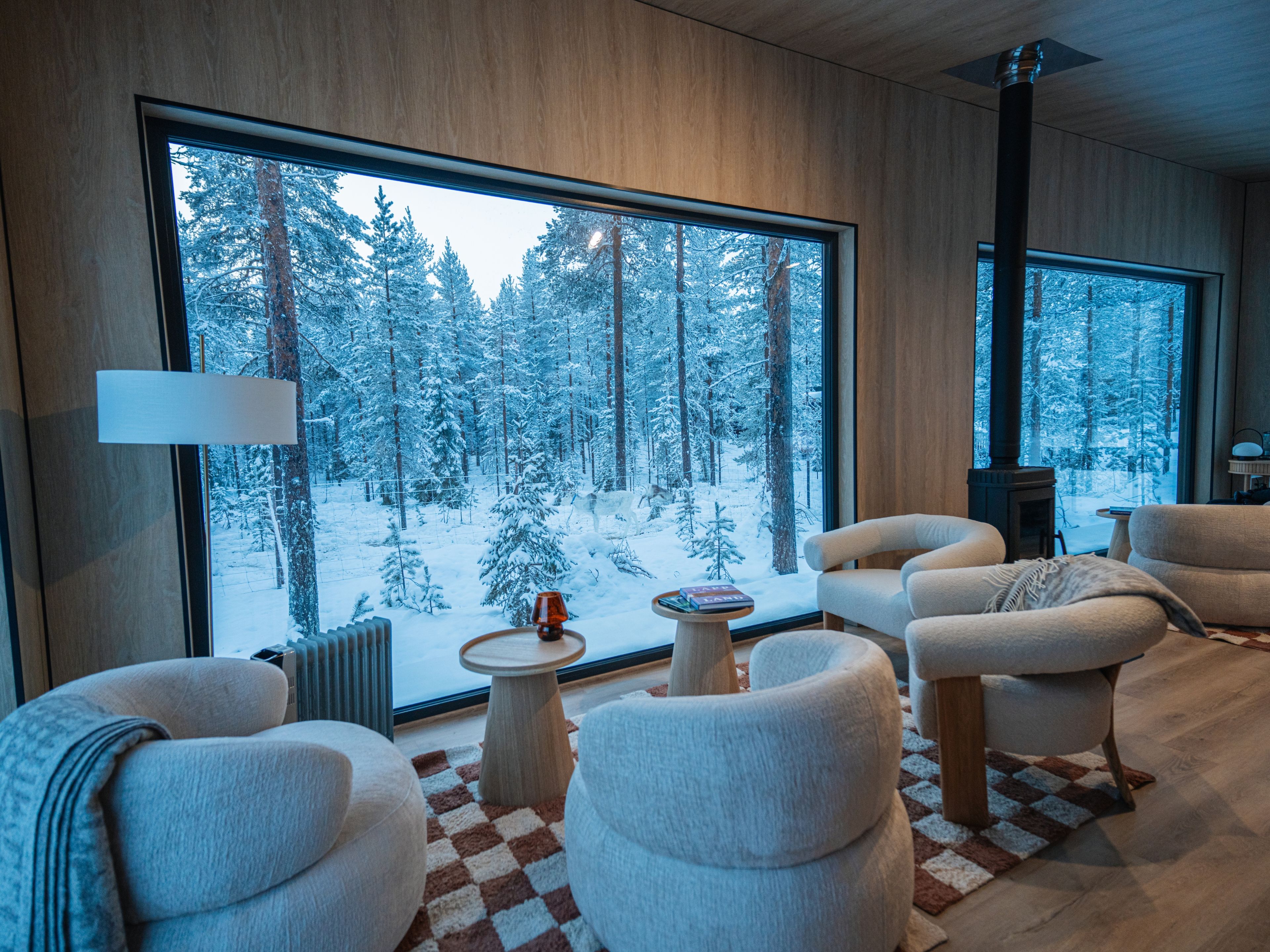 Una sala de estar moderna con ventanas amplias, chimenea y un rincón de descanso acogedor.