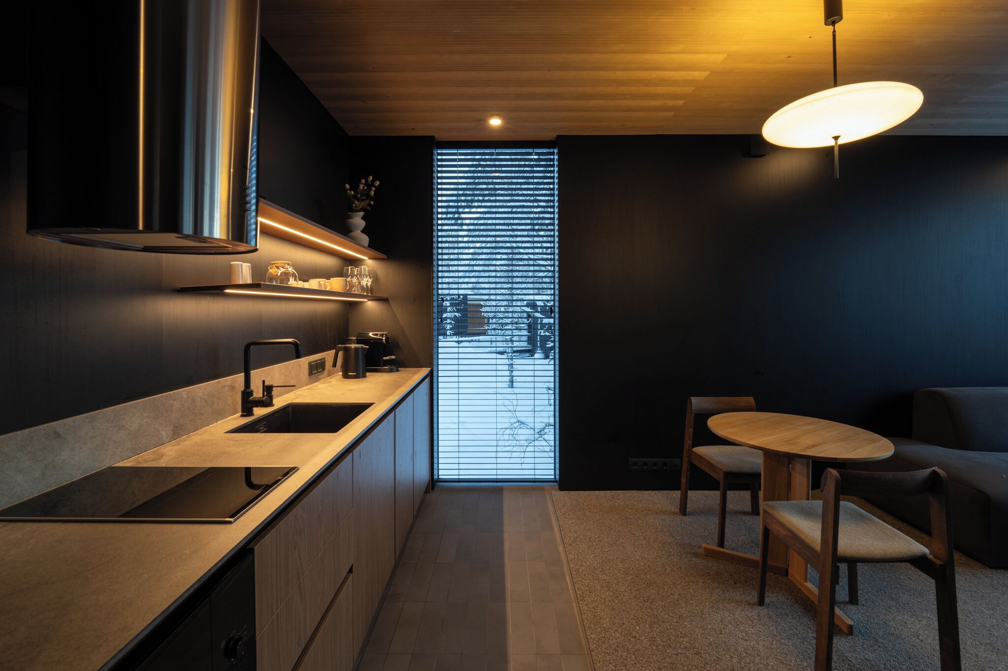 A modern kitchen with a built-in stove, a sink, and a dining area with a round table and chairs.