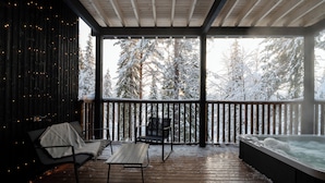 Eine Holzterrasse mit Whirlpool, zwei Stühlen und einem Tisch.
