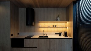 Eine moderne Küche mit Holzschränken, einer schwarzen Dunstabzugshaube und einem Regal mit Küchenutensilien.