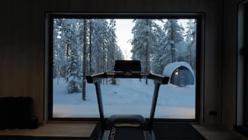 Juoksumatto huoneessa, jossa on suuri ikkuna, josta avautuu näkymä lumiseen metsään.