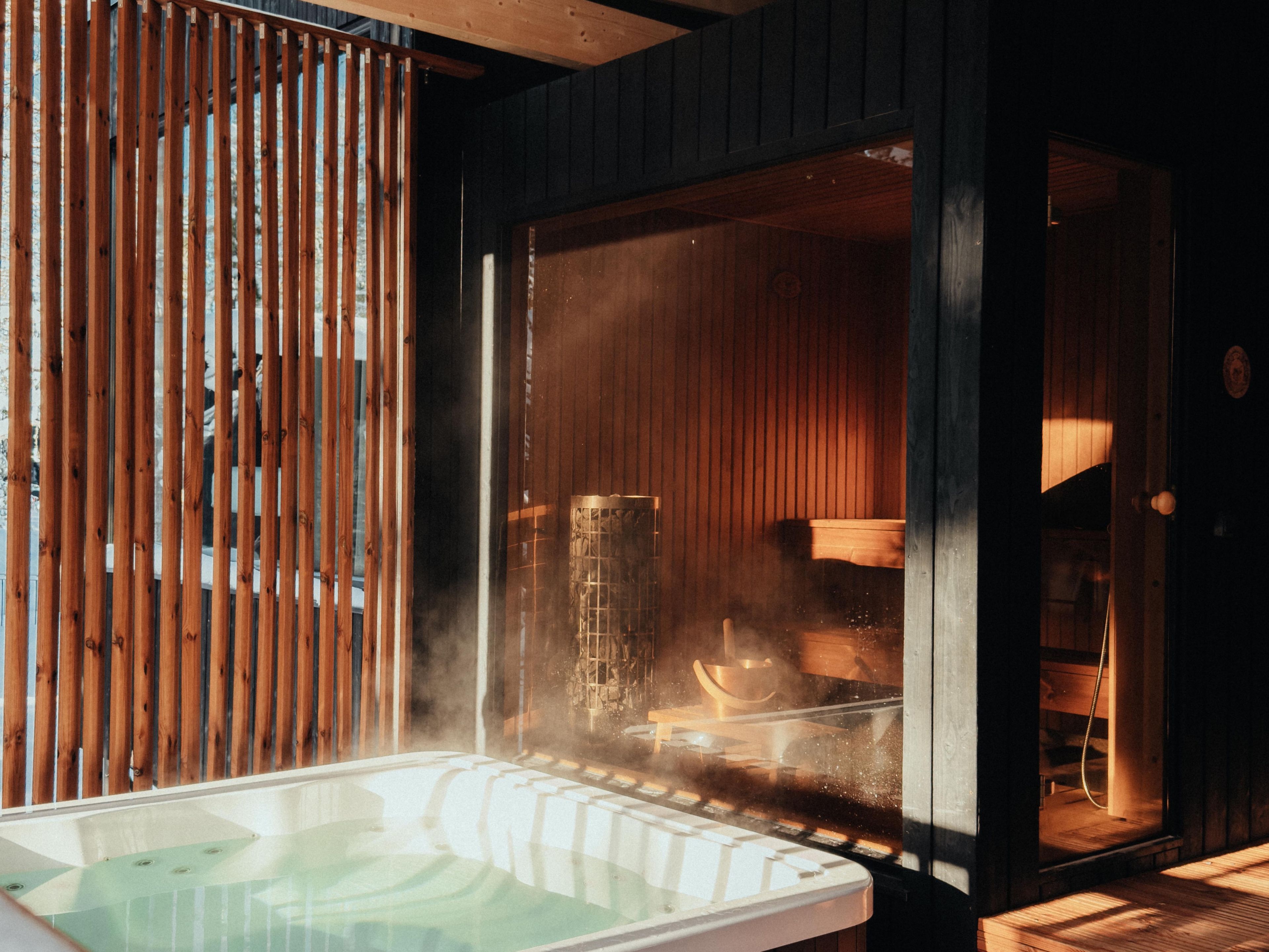 Un cuarto de sauna con recinto de vidrio, listones de madera y un banco.