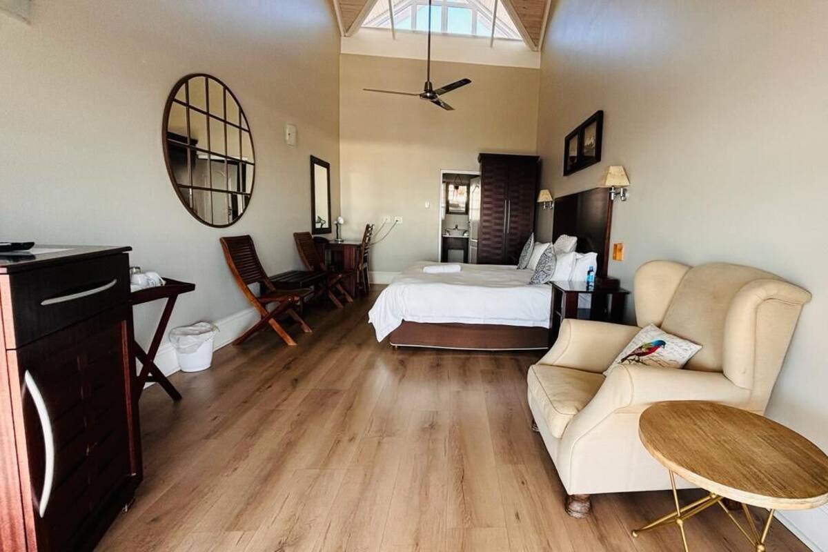 A spacious room with a bed, a desk, a chair, a sofa, and a small table.