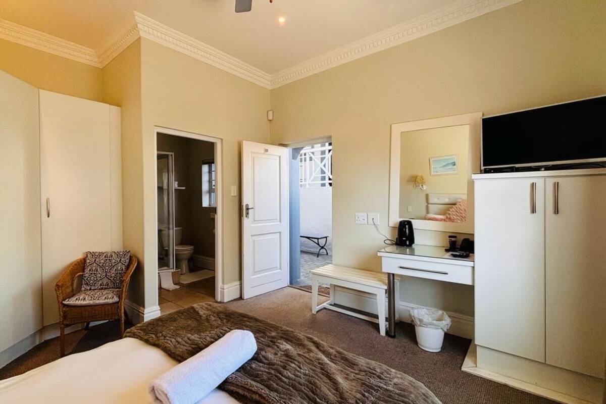 A hotel room with a bed, a desk, a chair, a television, and a wardrobe.