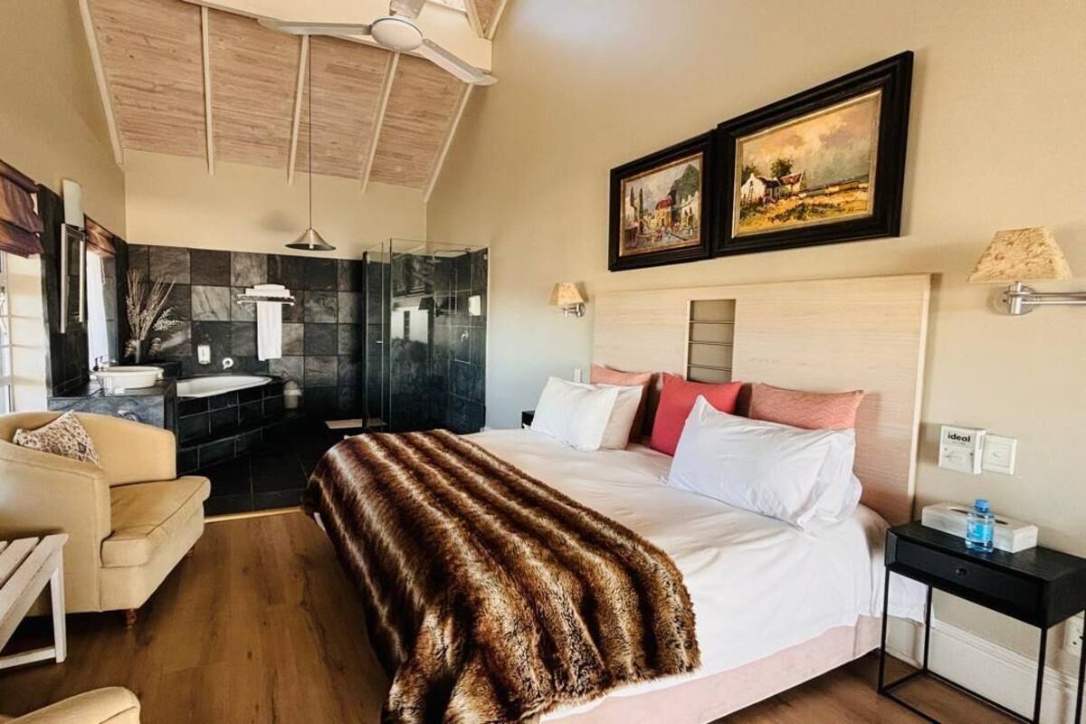 A hotel room with a bed, a sofa, a desk, a bathroom with a shower, and a window.