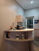 Una recepción con mostrador de madera, una puerta de vidrio que da a una habitación y un archivador con fundas azules.