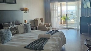 Ett modernt hotellrum med en stor säng, en takfläkt, en TV och en balkong med utsikt.
