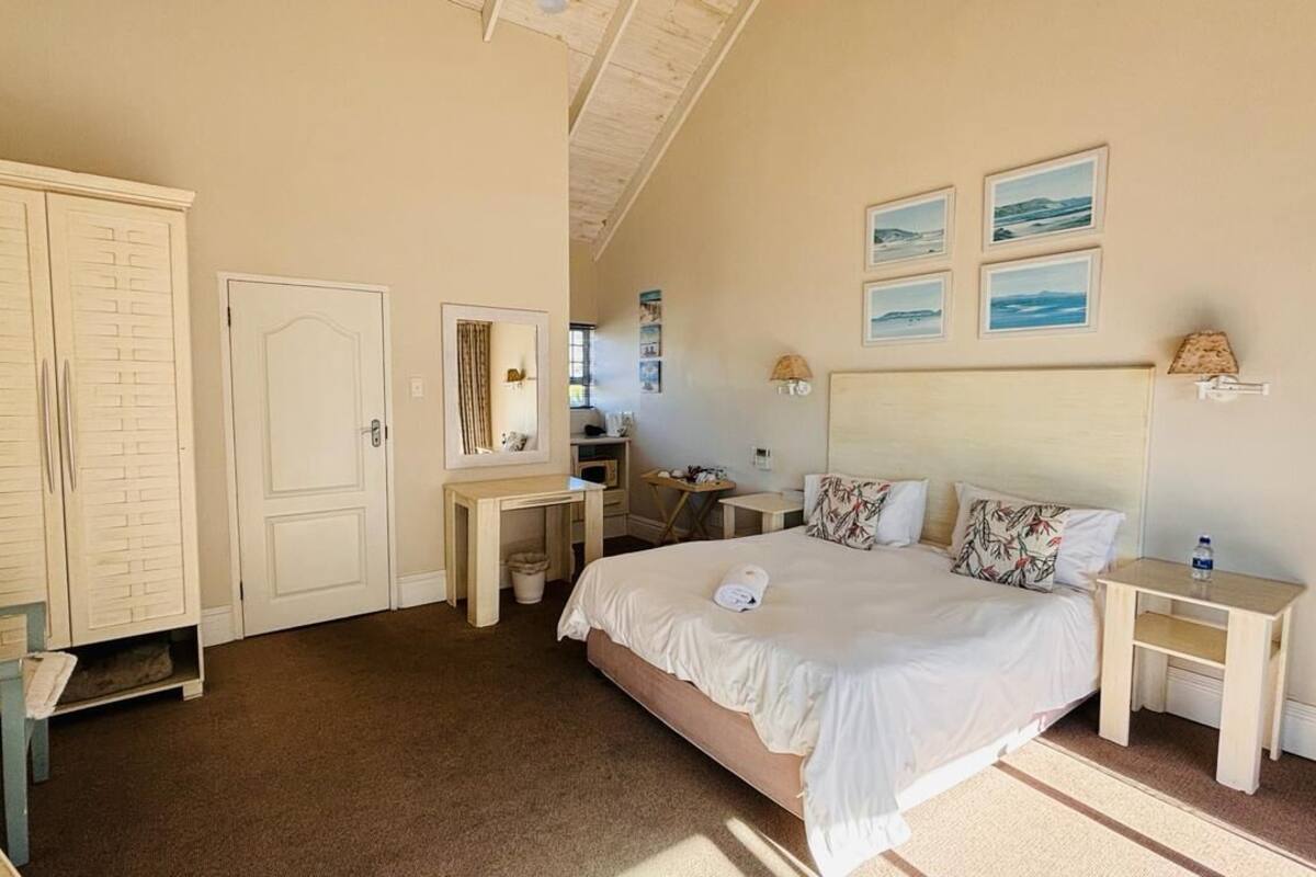 A bedroom with a bed, bedside tables, a wardrobe, a mirror, and artwork on the wall.