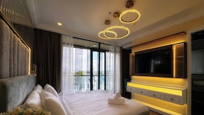 Una habitación de hotel moderna con una cama grande, una televisión de pantalla plana y un balcón con vistas a la ciudad.