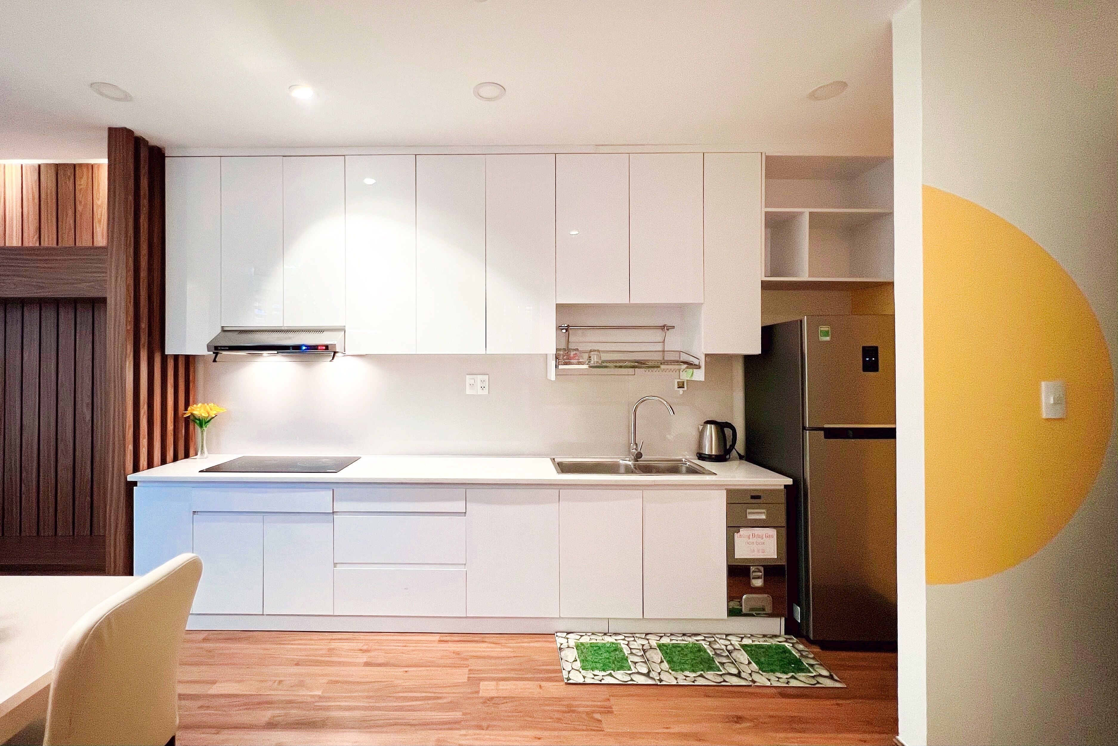 Una cocina moderna con armarios blancos, un lavamanos de acero inoxidable y un horno empotrado.
