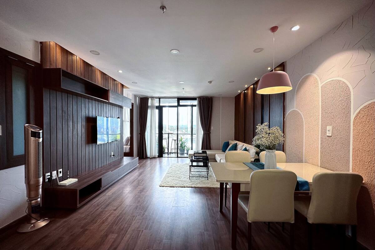A modern living room with a TV, sofa, dining table, and chairs.
