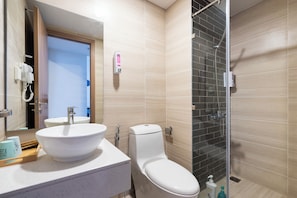 Et moderne badeværelse med en stor, hvid vask, toilet og et bruseområde med glasvægge.