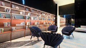 Een moderne bibliotheek met boekenkasten, donkerblauwe stoelen en neonverlichting.