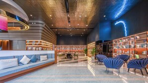 Een moderne bibliotheek met een gebogen zithoek, boekenkasten en een neonbord.
