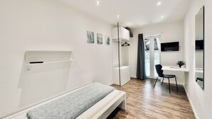 A modern, well-lit bedroom with a bed, a desk, and a chair. - ZIMMERzuVERMIETEN.ch Oensingen (Oensingen)