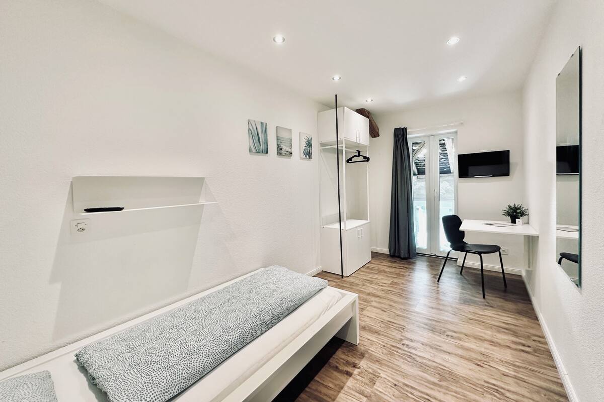 Une chambre à coucher moderne et bien éclairée, avec un lit, un bureau et une chaise.