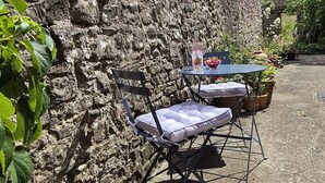 A stone wall with a small table and chair set against it.
