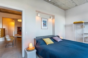 Un dormitorio con cama, lámparas de noche, un cuadro y un armario.