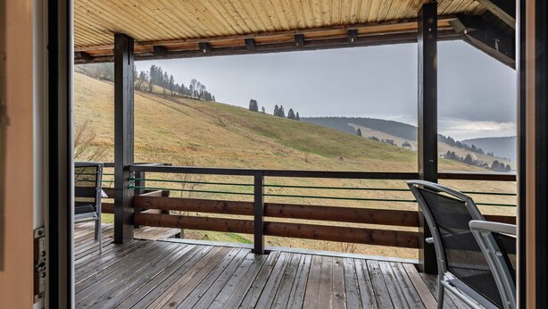 A wooden deck with a view of a hilly landscape.