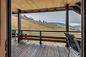 A wooden deck with a view of a hilly landscape.