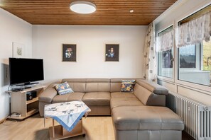 A modern living room with a sectional sofa, a flat-screen TV, a small table, and a radiator.