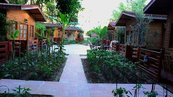 A pathway leading to wooden cabins with a garden area on either side.