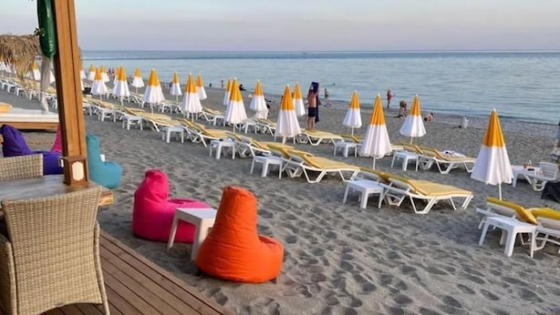 A beach with sun loungers and umbrellas, a wooden deck, and a clear view of the sea. - Şevki Bey Hotel (Alanya)