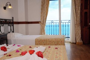 A hotel room with a bed, a nightstand, a window with a view of the sea, and a balcony with a railing. - Şevki Bey Hotel (Alanya)