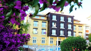 Ein Hotel mit Poolbereich, mehreren Balkonen und einer Mischung aus gelben und dunkel gefärbten Gebäuden.