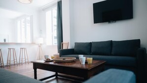 A modern living room with a dark blue sofa, a wooden coffee table with drinks, and a TV mounted on the wall. - La Maison sur la Loire-A stone's throw from the heart of Tours (Tours)