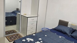 A bedroom with a bed, a dresser, a mirror, and a door. - SN Flats Nadera (Suva)