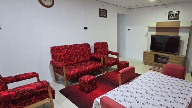 A compact living room with a sofa set, a TV, and a dining table. - SN Flats Nadera (Suva)