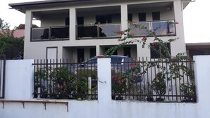 A multi-story residential building with balconies, a gated entrance, and a parked car. - SN Flats Nadera (Suva)