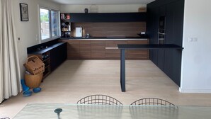 A modern kitchen with a central island, dark cabinetry, and a window providing natural light.