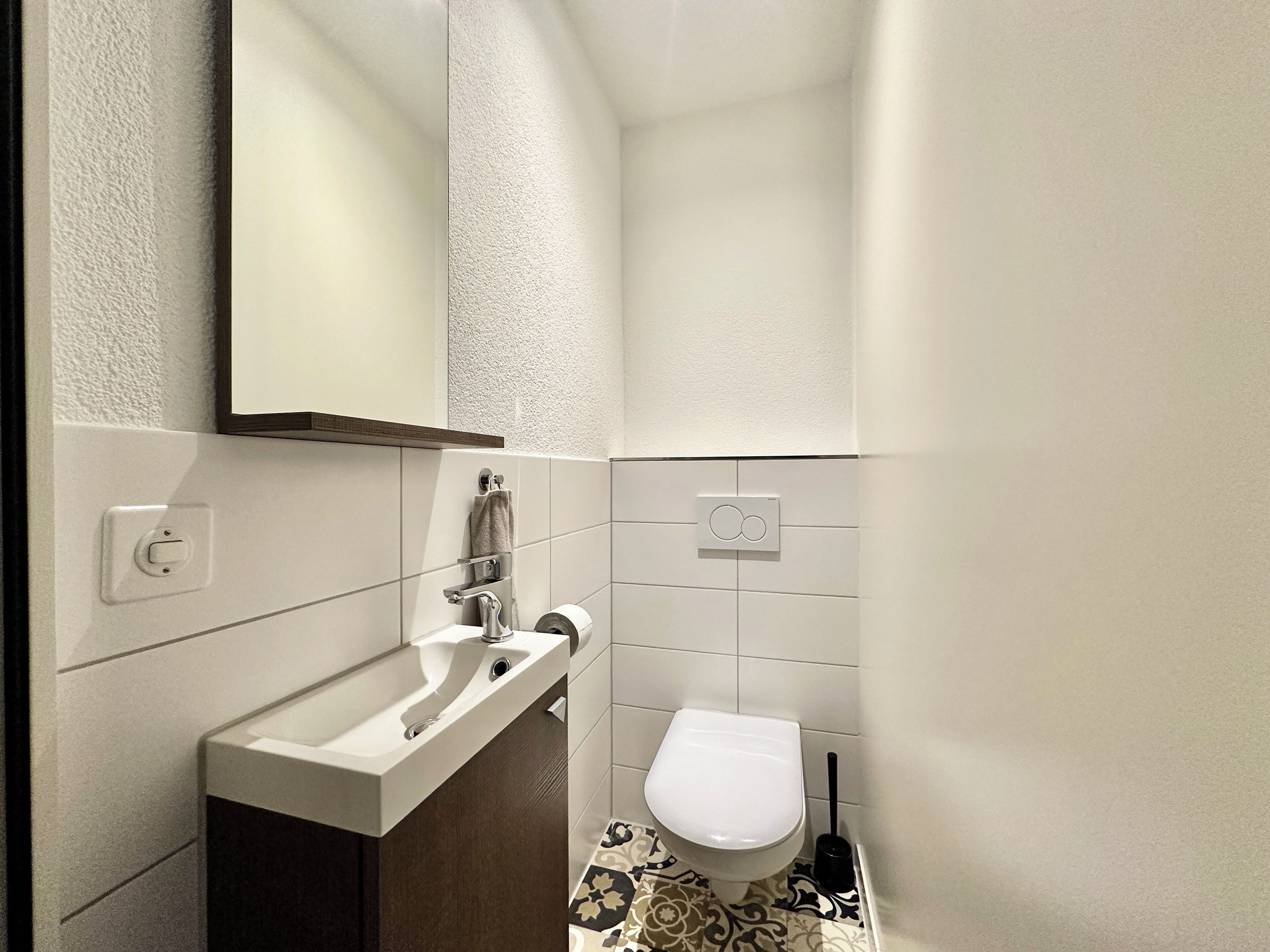 Un baño pequeño con un lavabo blanco, un inodoro y un espejo.