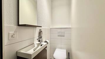 Un baño pequeño con un lavabo blanco, un inodoro y un espejo.