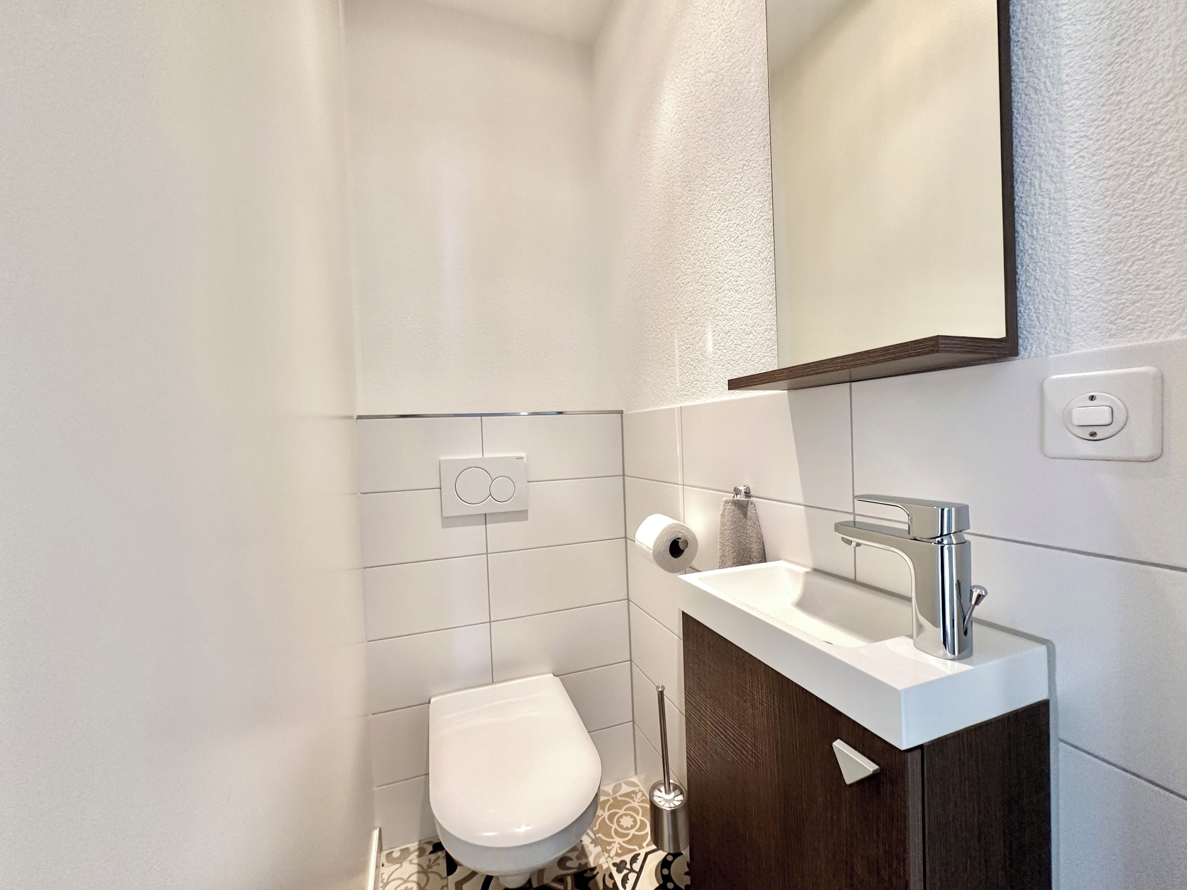 Ein modernes Badezimmer mit Toilette, Waschbecken mit Spiegel und Handtuchhalter.