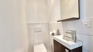 Ein modernes Badezimmer mit Toilette, Waschbecken mit Spiegel und Handtuchhalter.