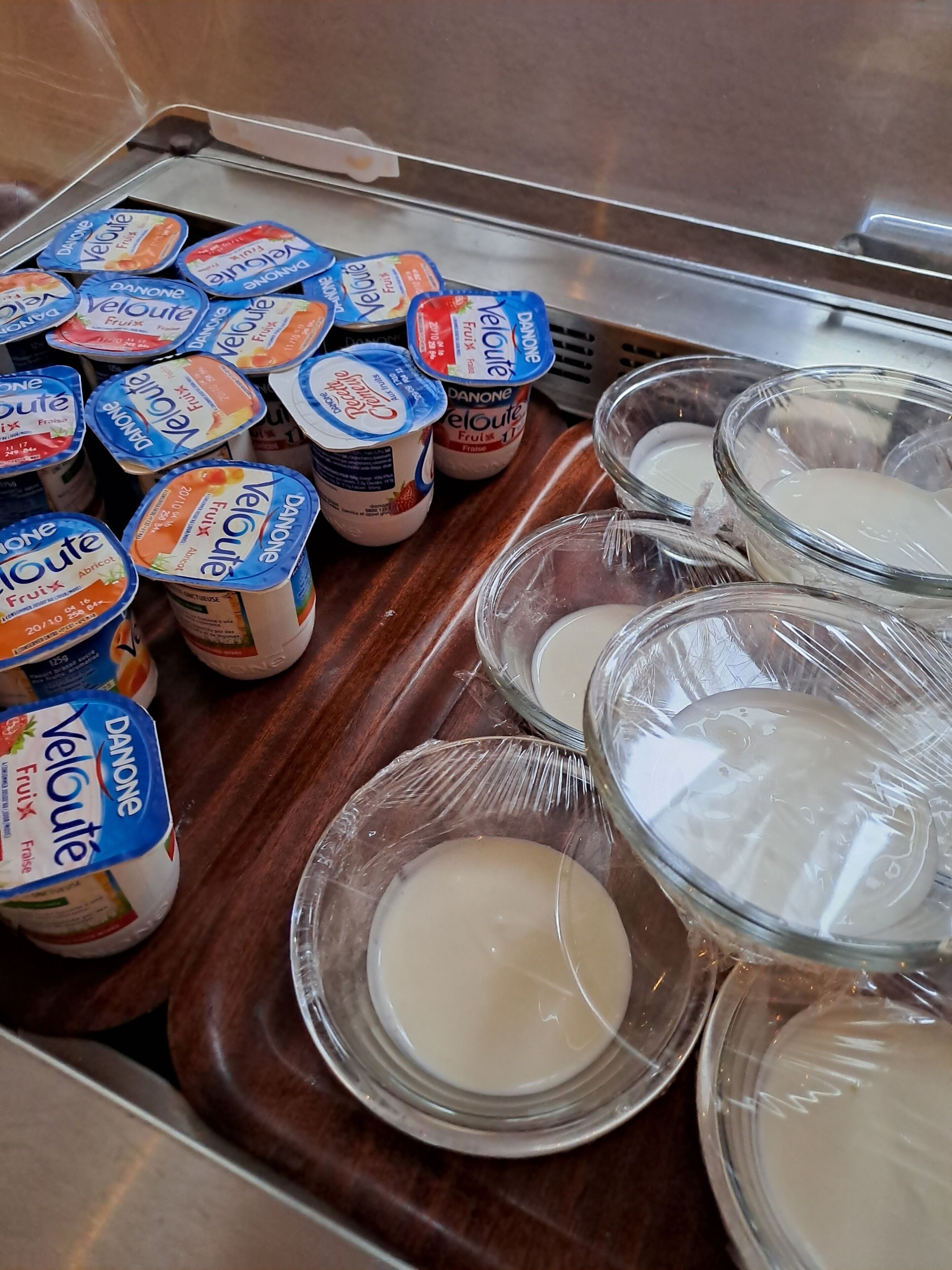 A selection of Danone Veloute yogurt containers and bowls of yogurt on a tray.