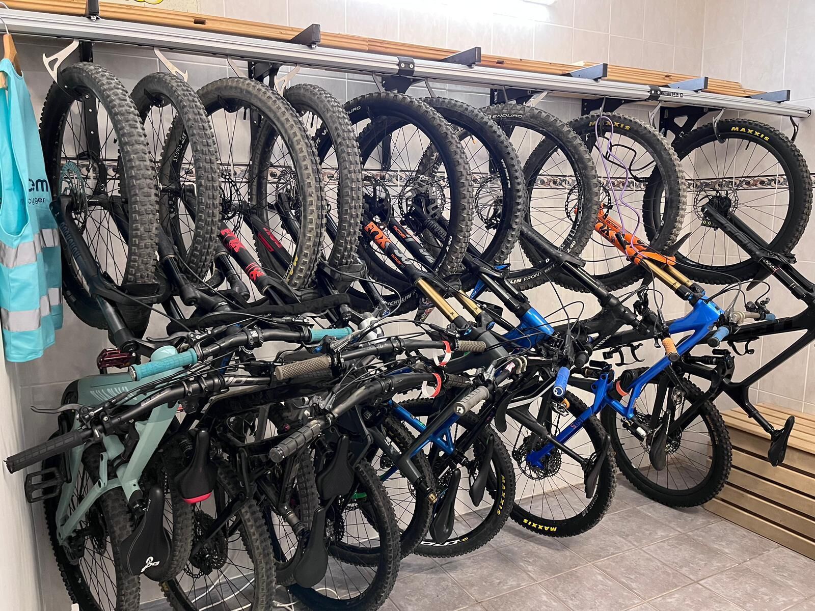 A bike rack with multiple bicycles and a blue bag hanging on the wall.