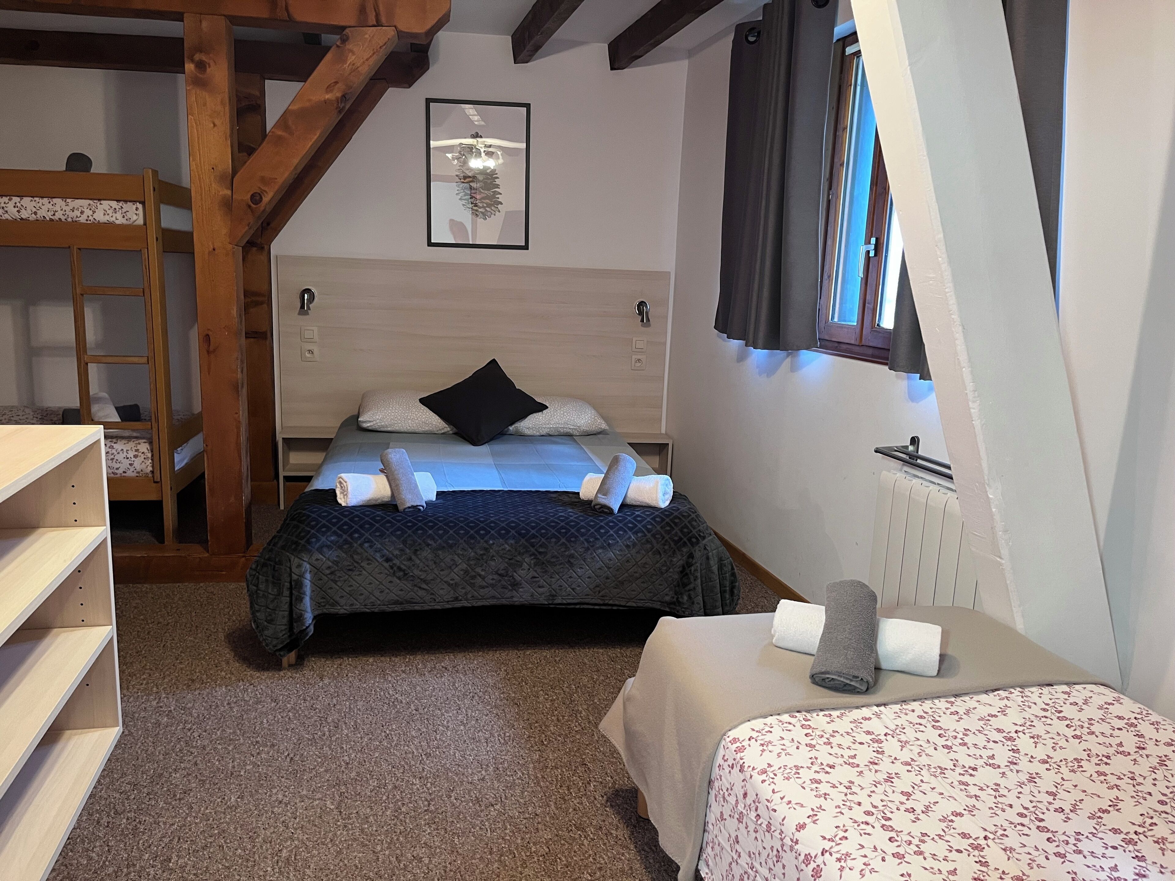 A bedroom with a bunk bed, a single bed, a wooden ladder, a radiator, and a framed picture on the wall.