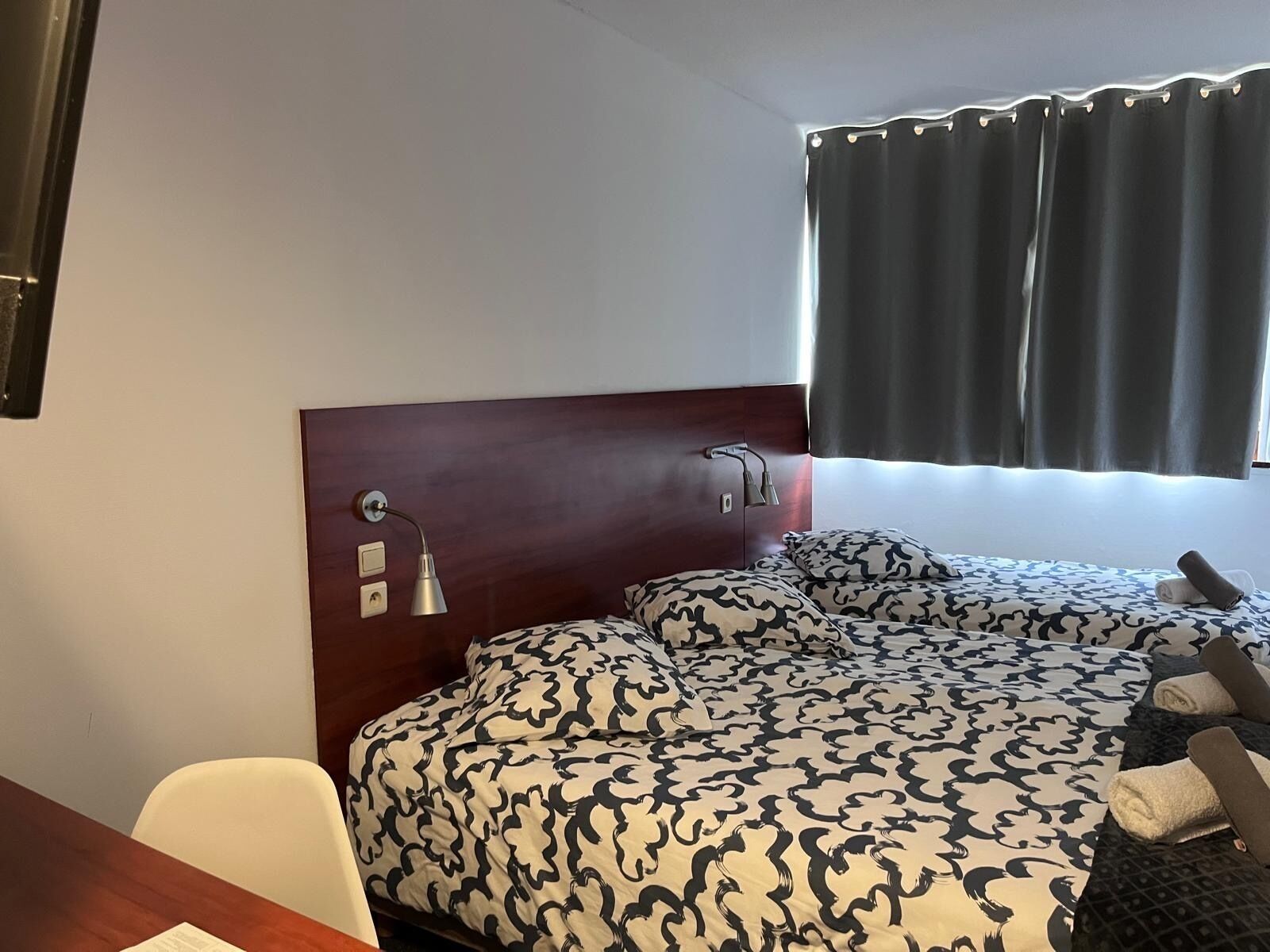 A hotel room with a bed, a desk, and a chair.