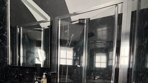 Une salle de bain moderne avec un meuble-lavabo blanc, un grand miroir et une douche à parois de verre.