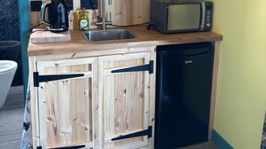 Une cuisine compacte dotée de meubles en bois, d’un évier, d’un four à micro-ondes et d’une machine à café.