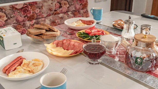 A breakfast table with various food items, a coffee cup, and a salt shaker. - Camping Yard Hostel Karakol (Karakol)