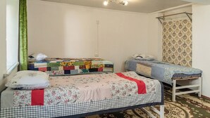 A room with two beds, a patterned quilt, a green curtain, and a patterned wall. - Camping Yard Hostel Karakol (Karakol)