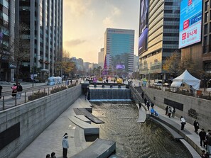 Een stadsbeeld met moderne gebouwen, een waterpartij en mensen die lopen.