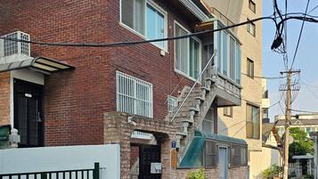A two-story brick building with a small balcony, a staircase, and a green awning.