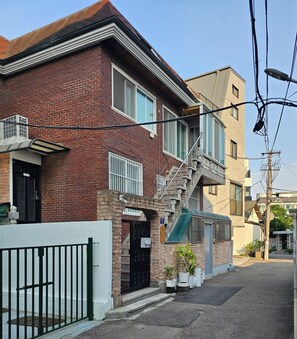 A two-story brick building with a small balcony, a staircase, and a green awning.